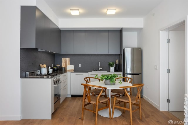 kitchen with tasteful backsplash, stainless steel appliances, sink, light hardwood / wood-style flooring, and gray cabinets