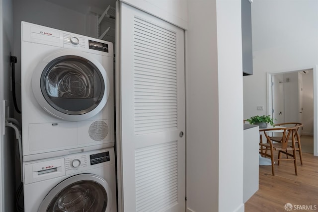 washroom with light wood-type flooring and stacked washer / dryer