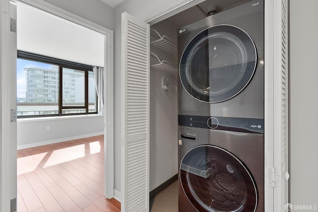 laundry area featuring light wood-type flooring and stacked washer and clothes dryer