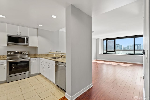 kitchen featuring sink, white cabinets, stainless steel appliances, and light wood-type flooring