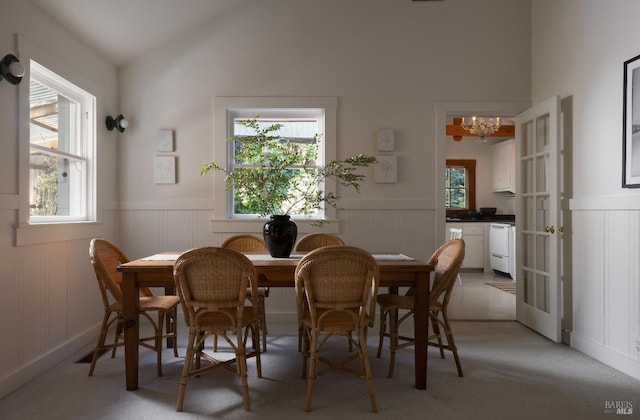 2770 Bohemian Hwy, Occidental, CA 95465 - dining room featuring a decorative wall, a chandelier, wainscoting, light colored carpet, and vaulted ceiling