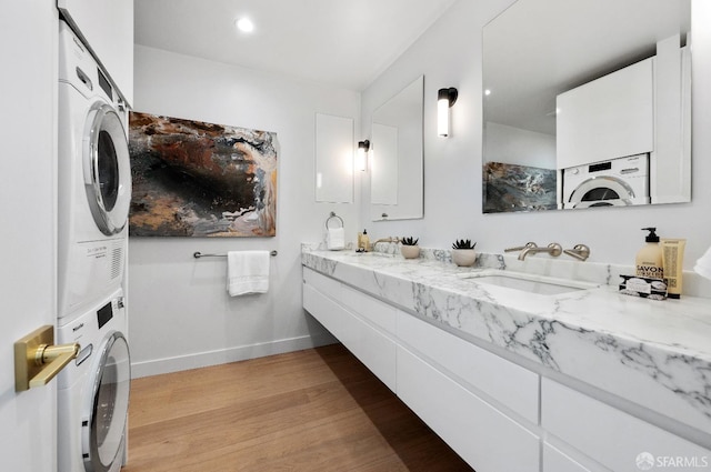 bathroom with wood-type flooring, stacked washer / drying machine, and vanity