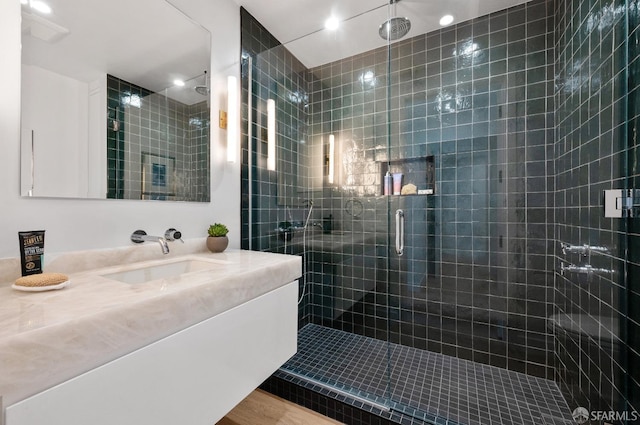 bathroom with wood-type flooring, a shower with door, and vanity