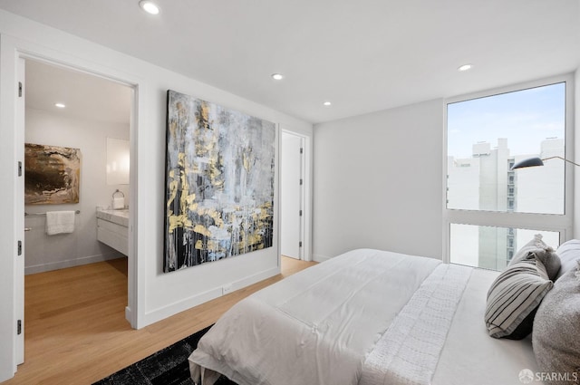 bedroom featuring ensuite bath and light hardwood / wood-style flooring