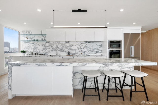 kitchen featuring a large island, white cabinets, light hardwood / wood-style flooring, and a breakfast bar area