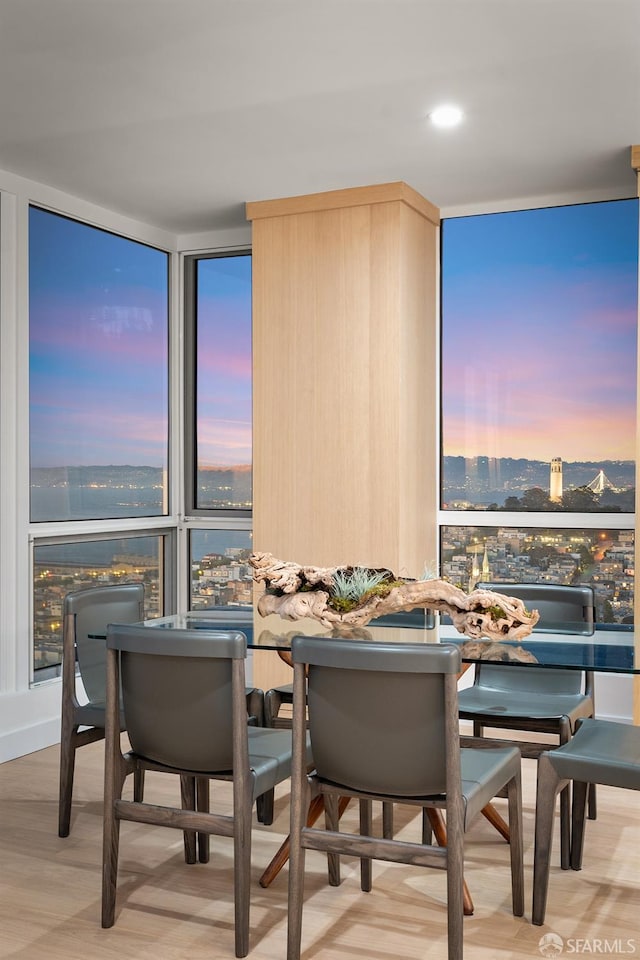 dining area featuring light wood-type flooring, a water view, a wall of windows, and a fireplace