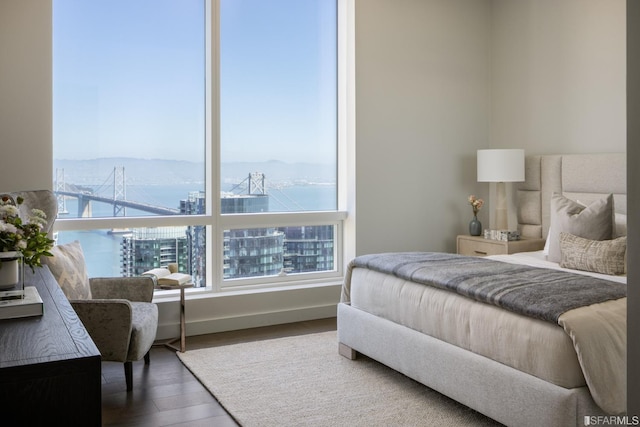 bedroom with a water view and hardwood / wood-style flooring