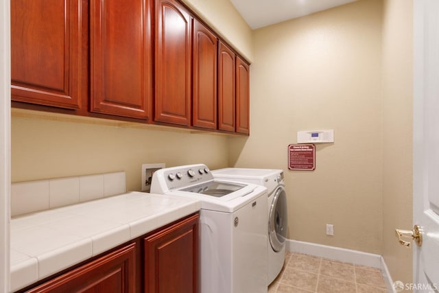 clothes washing area with cabinets, light tile patterned floors, and washing machine and dryer