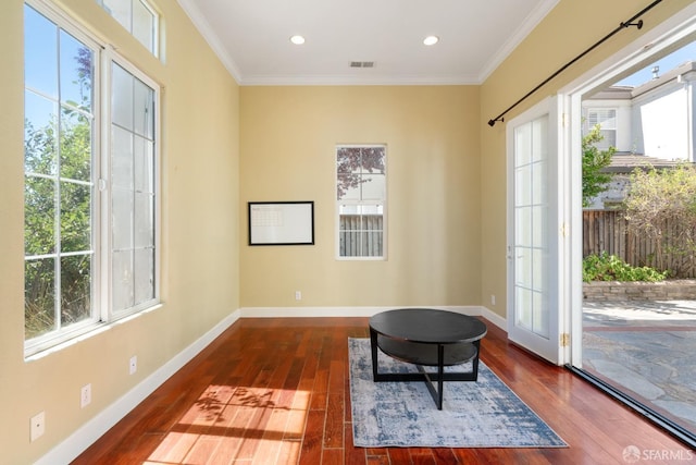 living area featuring dark hardwood / wood-style flooring, plenty of natural light, and ornamental molding