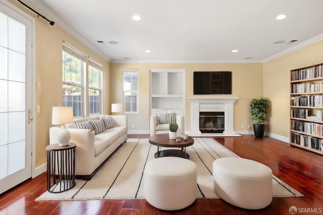 living room featuring hardwood / wood-style flooring, built in features, and crown molding