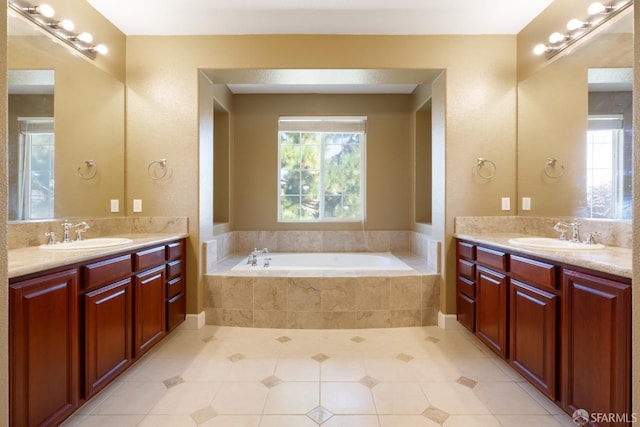 bathroom featuring tile patterned floors, tiled bath, and vanity