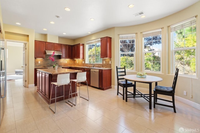 kitchen featuring sink, a center island, stainless steel appliances, backsplash, and light tile patterned floors