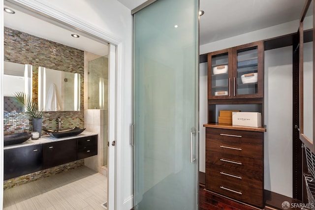 bathroom with a stall shower, vanity, and decorative backsplash