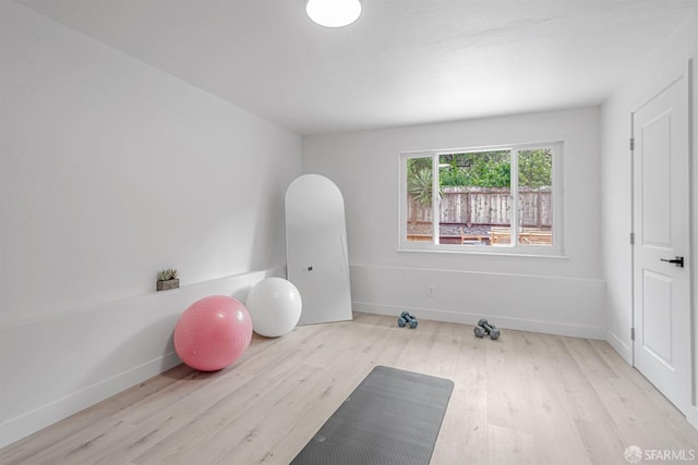 workout area with baseboards and wood finished floors