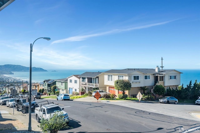 view of road featuring curbs, traffic signs, a residential view, street lights, and sidewalks