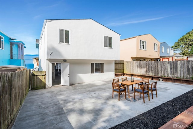 back of house with a fenced backyard, stucco siding, outdoor dining area, and a patio