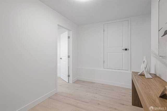 corridor featuring baseboards and light wood-style floors