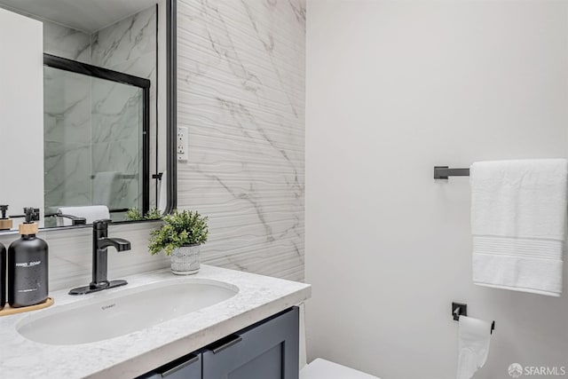 bathroom with a marble finish shower, toilet, and vanity