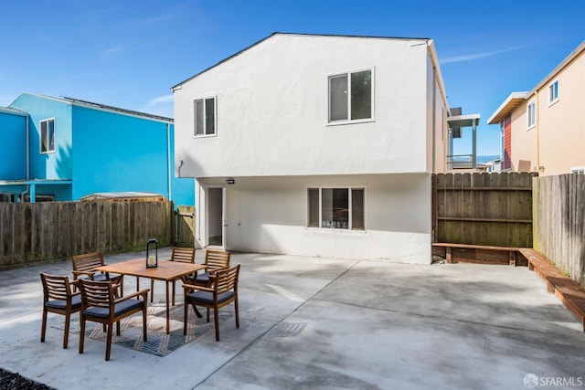 rear view of house featuring a patio area, stucco siding, outdoor dining area, and a fenced backyard