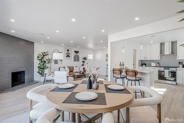 dining space with a fireplace, recessed lighting, and light wood finished floors