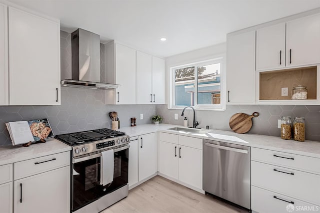 kitchen featuring stainless steel appliances, light countertops, wall chimney range hood, and a sink