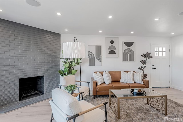 living area featuring recessed lighting, a brick fireplace, baseboards, and wood finished floors