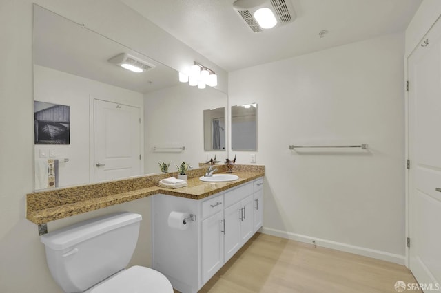 bathroom featuring vanity, wood finished floors, visible vents, baseboards, and toilet