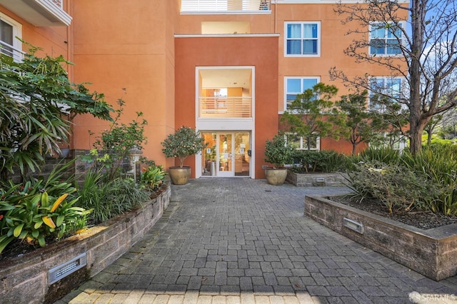 doorway to property with stucco siding, visible vents, and french doors