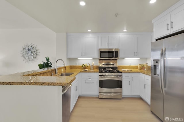 kitchen featuring a sink, appliances with stainless steel finishes, a peninsula, and white cabinets