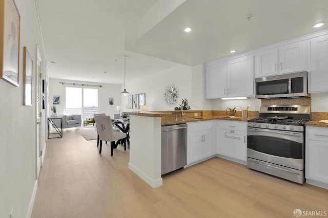 kitchen featuring white cabinetry, light wood-style floors, open floor plan, and appliances with stainless steel finishes