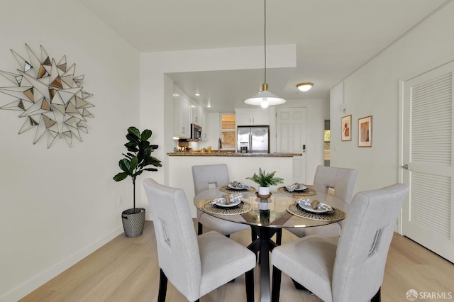 dining area featuring baseboards and light wood finished floors