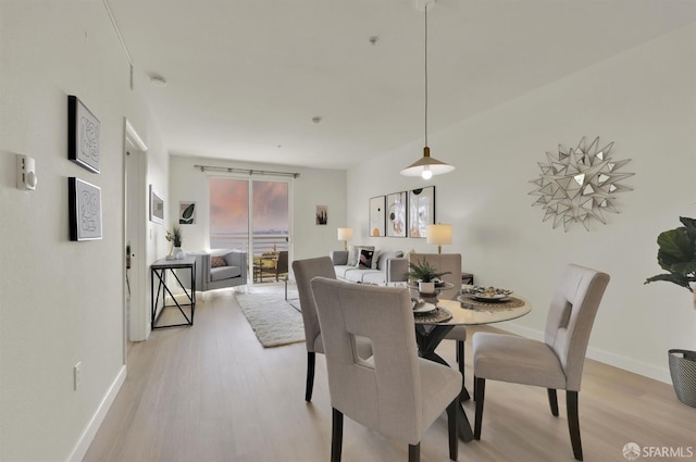 dining space with baseboards and light wood-type flooring