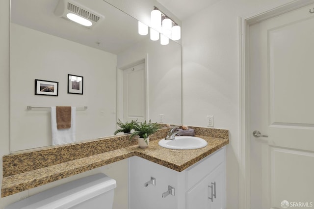 bathroom featuring visible vents, toilet, and vanity