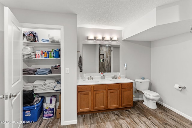 4750 E Soft Pit Hill Rd, Hartsburg, MO 65039 - bathroom featuring wood finished floors, double vanity, toilet, a shower, and a textured ceiling