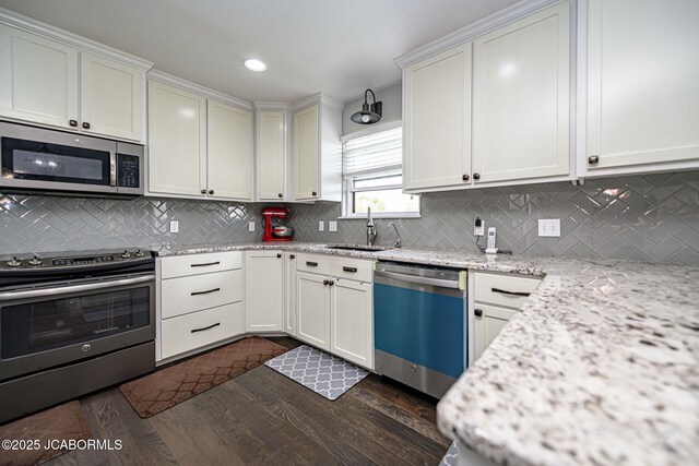 kitchen with stainless steel appliances, a sink, dark wood finished floors, backsplash, and light stone counters
