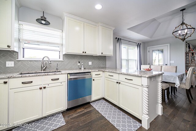 kitchen featuring a peninsula, a sink, a chandelier, dishwasher, and dark wood-type flooring