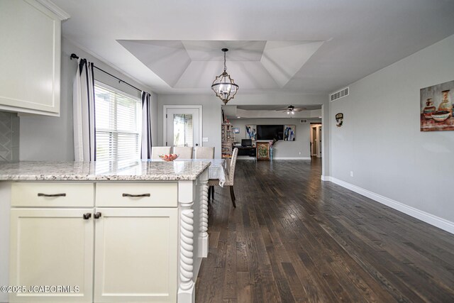 kitchen with white cabinets, a tray ceiling, dark wood finished floors, a peninsula, and visible vents