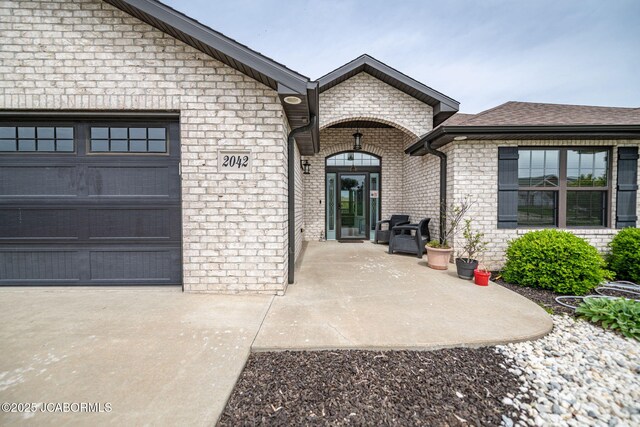 view of exterior entry featuring brick siding and a garage