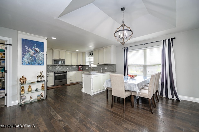 dining room with recessed lighting, dark wood-style floors, an inviting chandelier, a raised ceiling, and baseboards