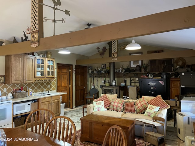 interior space featuring vaulted ceiling with beams, a wood stove, and sink