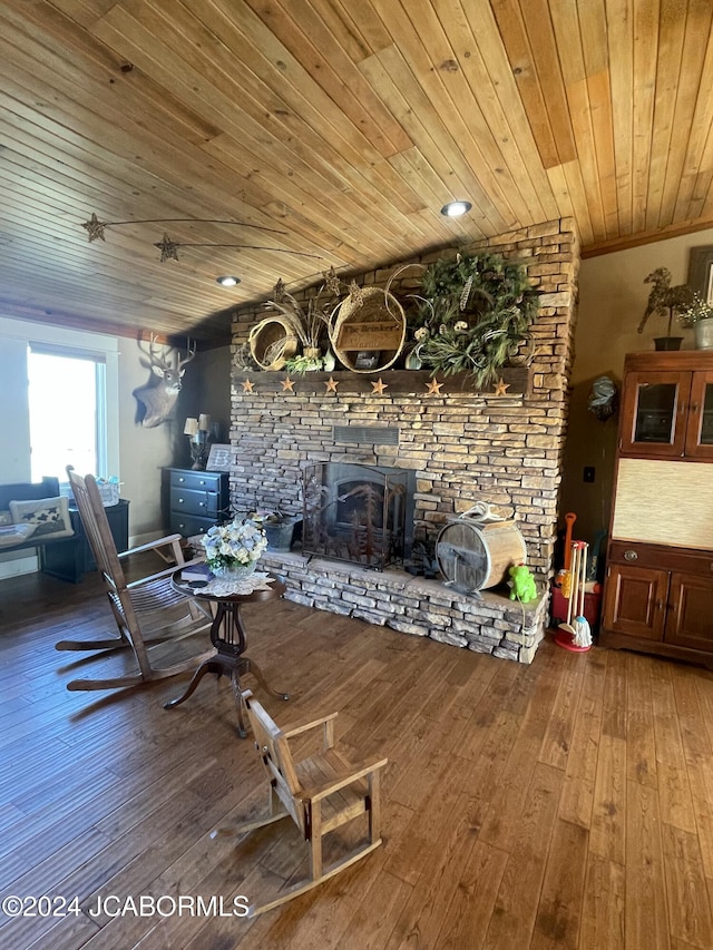 living room with hardwood / wood-style flooring, a stone fireplace, wood ceiling, and ornamental molding