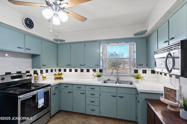 kitchen with ceiling fan, a sink, light countertops, appliances with stainless steel finishes, and backsplash