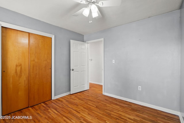 unfurnished bedroom with a closet, a ceiling fan, baseboards, and wood finished floors