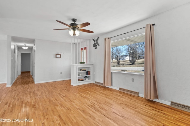 unfurnished living room with light wood-style flooring, a ceiling fan, visible vents, and baseboards