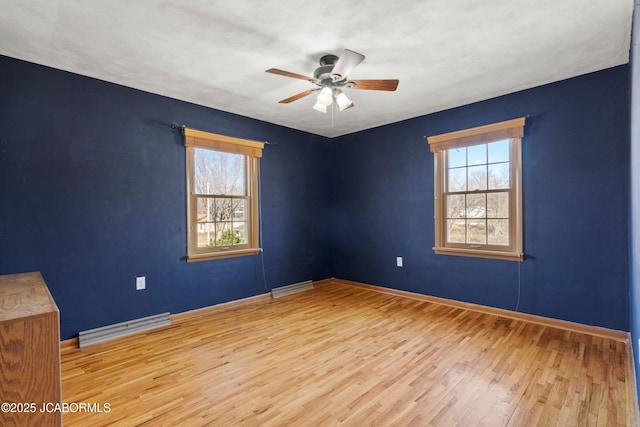 empty room featuring a wealth of natural light, baseboards, ceiling fan, and wood finished floors