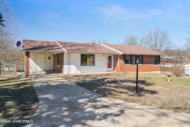 ranch-style house with driveway, fence, roof with shingles, a carport, and brick siding