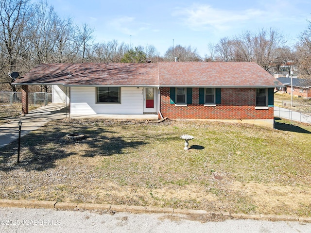 ranch-style house with brick siding, fence, a front yard, a carport, and driveway