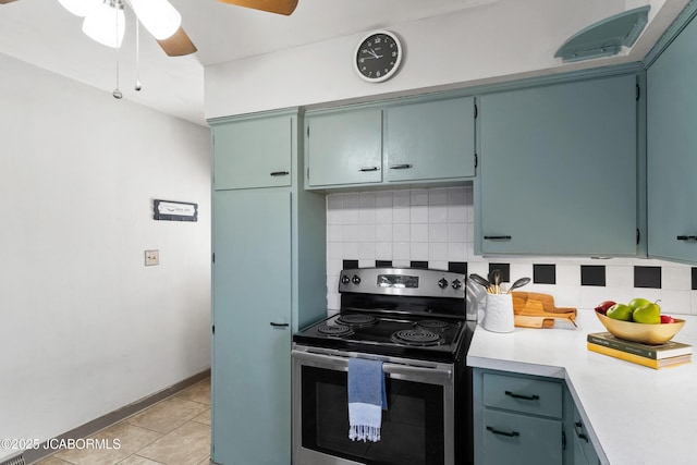 kitchen with electric range, a ceiling fan, light countertops, light tile patterned floors, and decorative backsplash