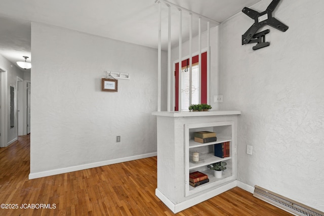 interior space with wood finished floors, visible vents, a textured wall, and baseboards