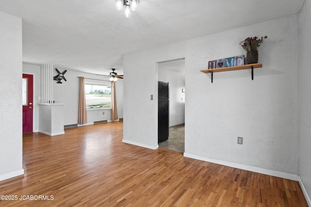 spare room featuring baseboards, ceiling fan, and light wood finished floors